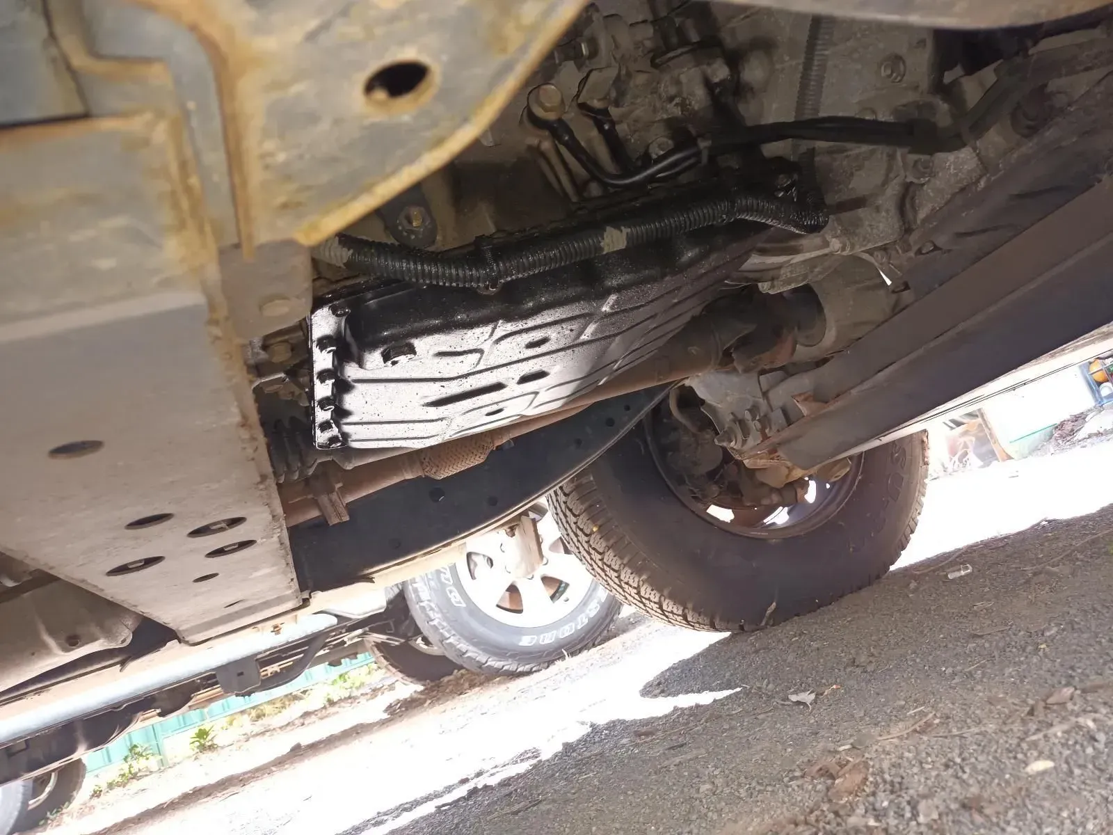 Underside of a Vehicle, Showing a Black Skid Plate, Tyre, and Rusty Frame — South West 4WD Wreckers In Brisbane, QLD