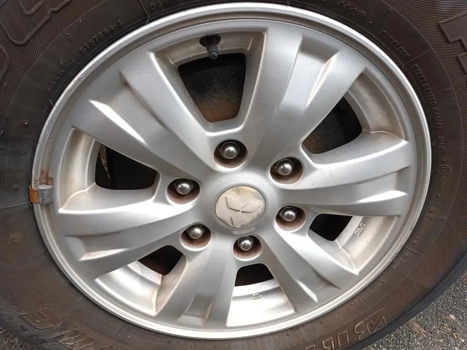 Silver Car Wheel With Tyre, Showing Bolts and a Damaged Center Cap — South West 4WD Wreckers In Brisbane, QLD
