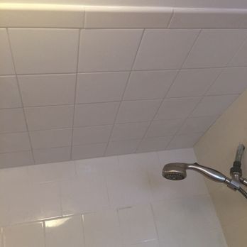 White tiled shower ceiling and wall with a silver showerhead.