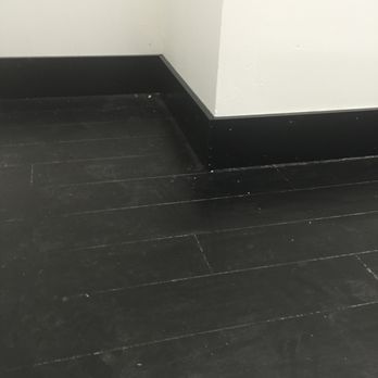 Black baseboard and wood floor meet white wall at corner.