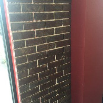 Dark brick wall beside a red wall, near a window frame.