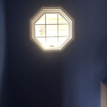 Octagonal window with nine panes, centered on a dark blue wall. Sunlight streams through.