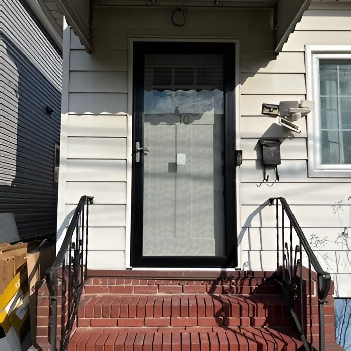 Brick steps lead up to a white house with black screen door. Black railing on sides.