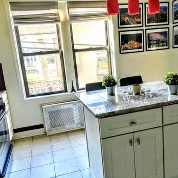 Kitchen with white cabinets, granite countertop island, windows, and framed pictures.