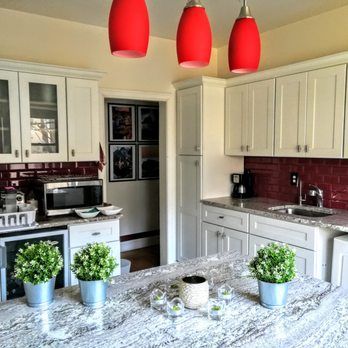 Bright kitchen with white cabinets, red backsplash, and three red pendant lights.