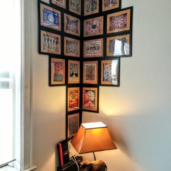 Corner wall with framed art and a lit lamp on a table below.