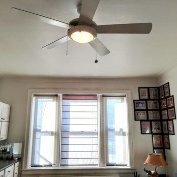 Ceiling fan with light fixture over windows. Wall art in the corner.