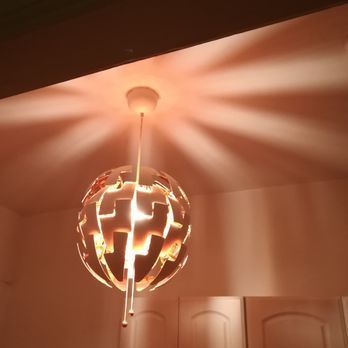White, globe-shaped pendant lamp casting light patterns on a ceiling.