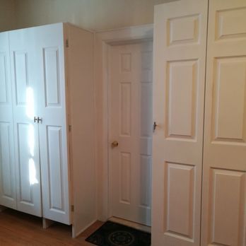 White cabinets flank a doorway with a closed white door. A dark doormat is visible.