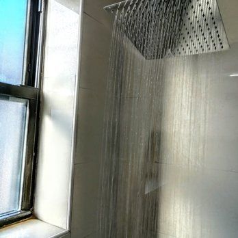 Shower head with water streams flowing downwards; next to a window.