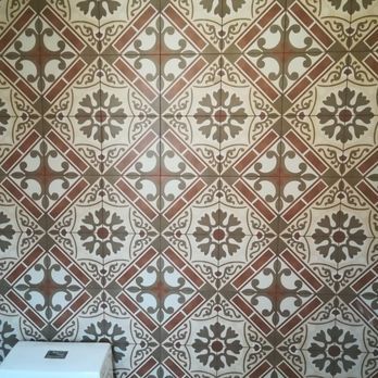 Tiled wall with repeating floral and geometric patterns in shades of brown, gray, and white.