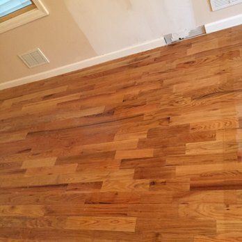 Wood floor in a room, angled view. Beige walls, white trim, and a small vent.