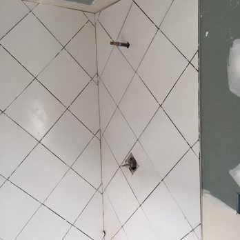 White diamond-patterned tile shower walls with black grout; plumbing fixtures visible.