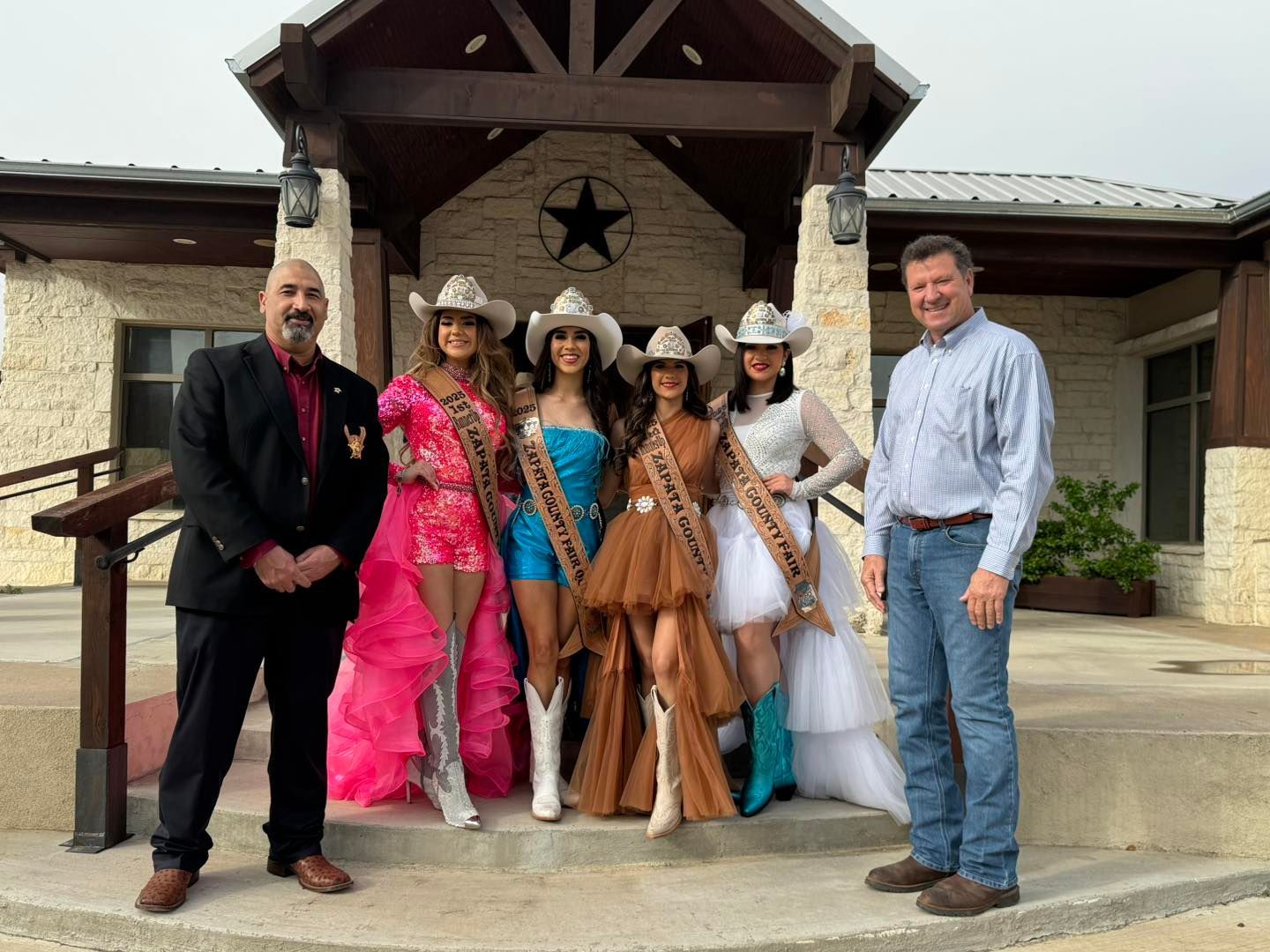 A group of people standing in front of a building wearing cowboy hats.