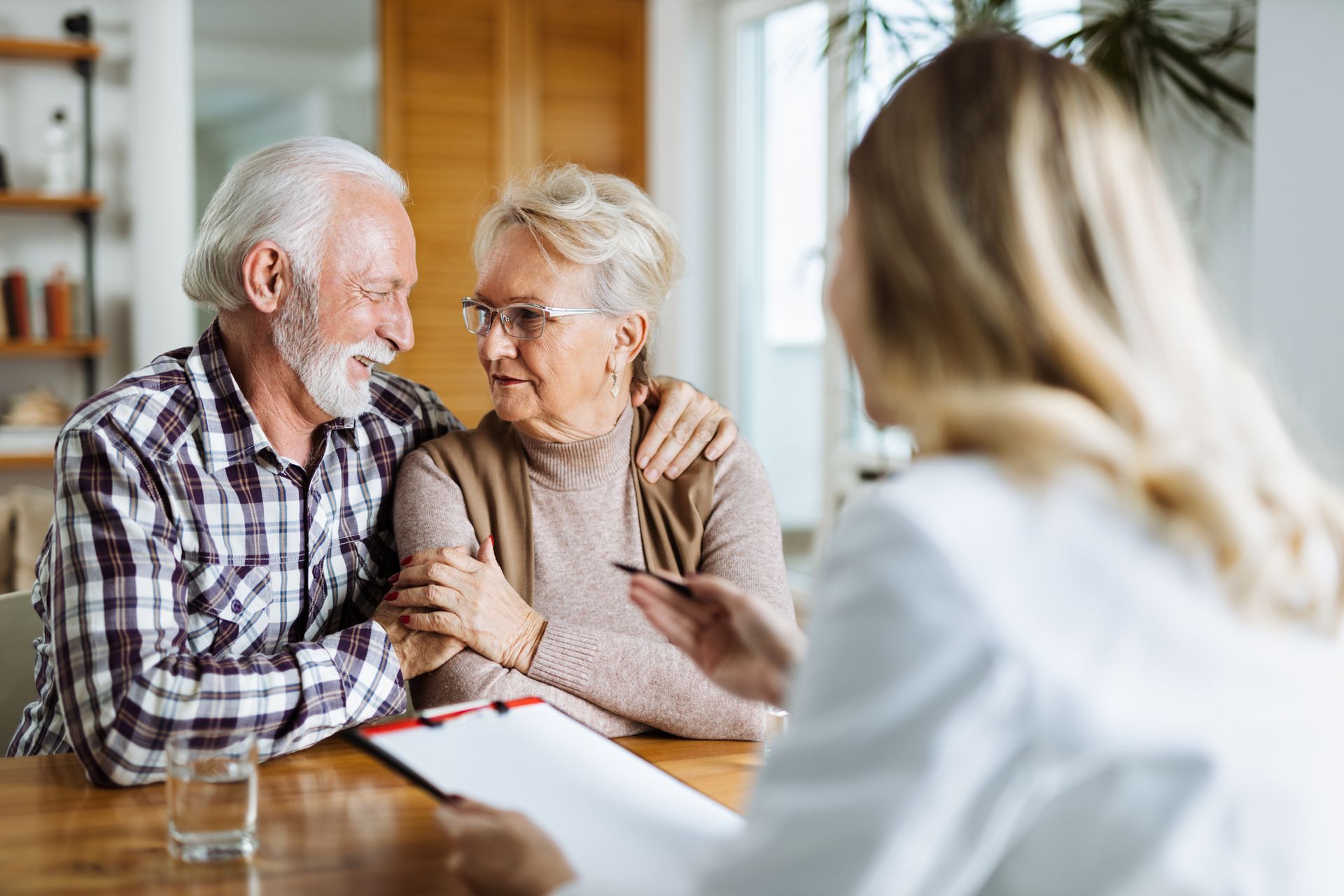 An elderly couple is sitting at a table talking to a doctor.