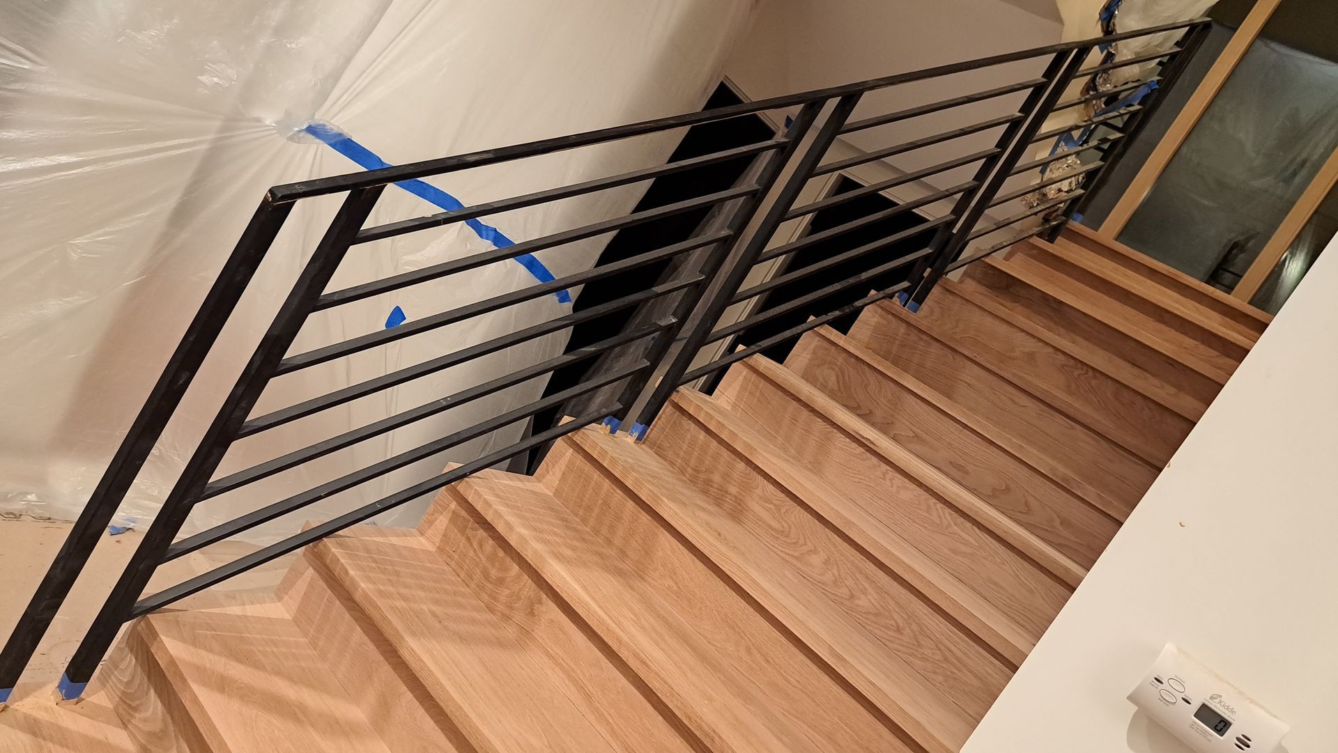 Wooden staircase with black metal railing.
