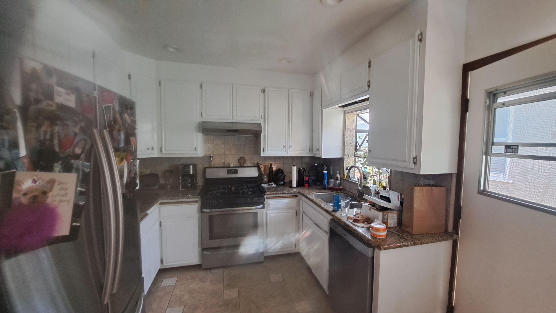 Kitchen with white cabinets, stainless steel appliances, and a window.
