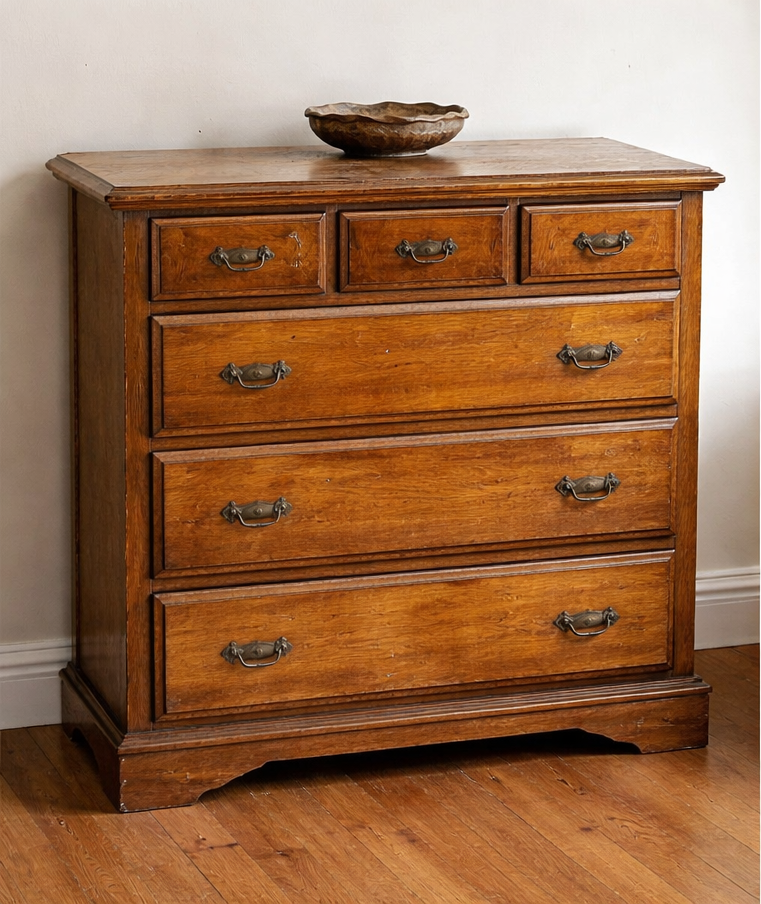 Wooden dresser with five drawers, bronze handles, and a bowl on top.