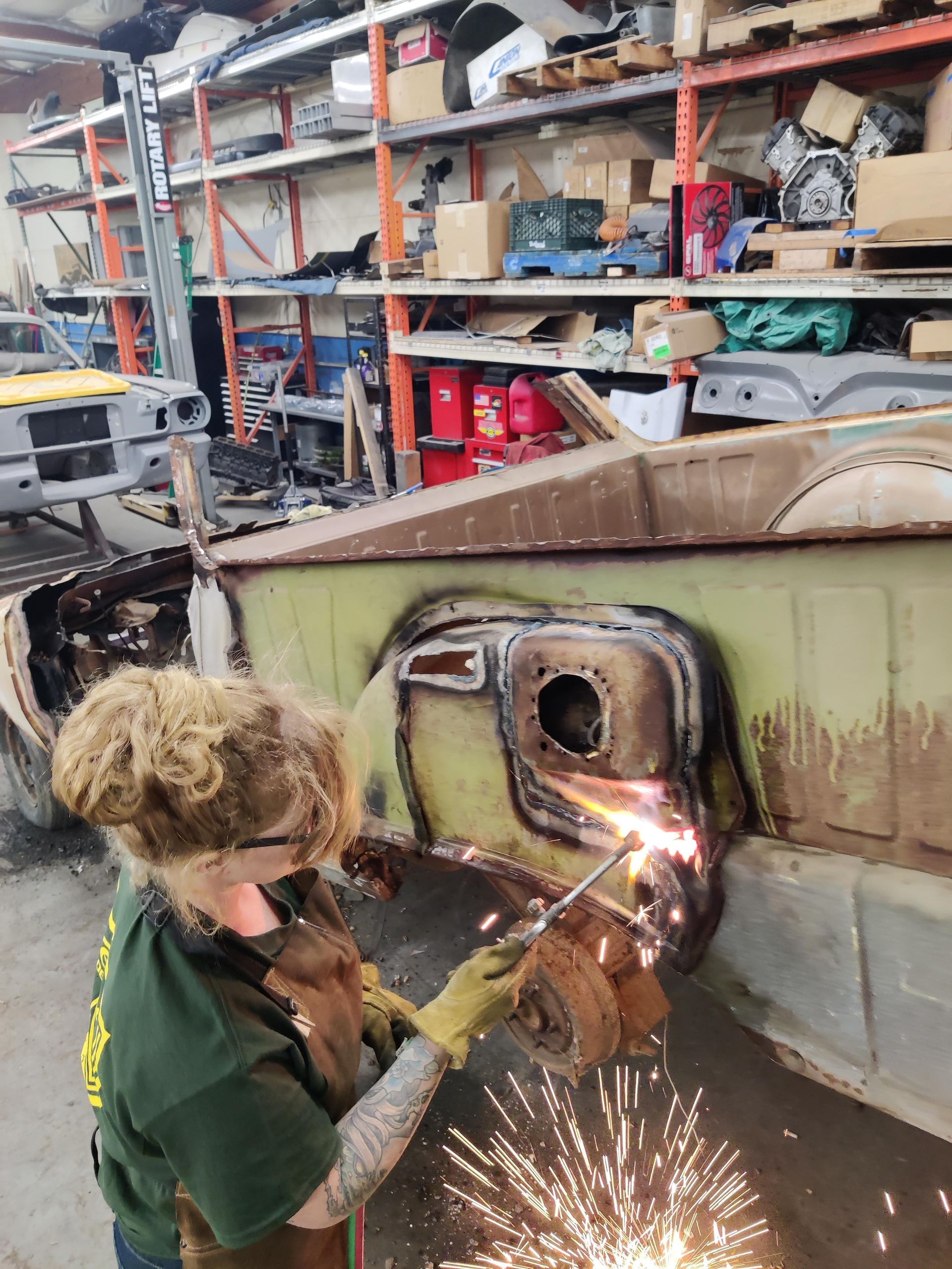 Person using a torch to cut metal on a car in a workshop, sparks flying.