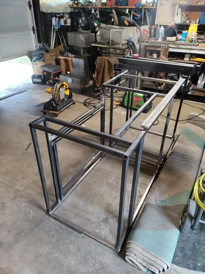 Welded metal frames in a garage workshop, likely for a table or workstation.