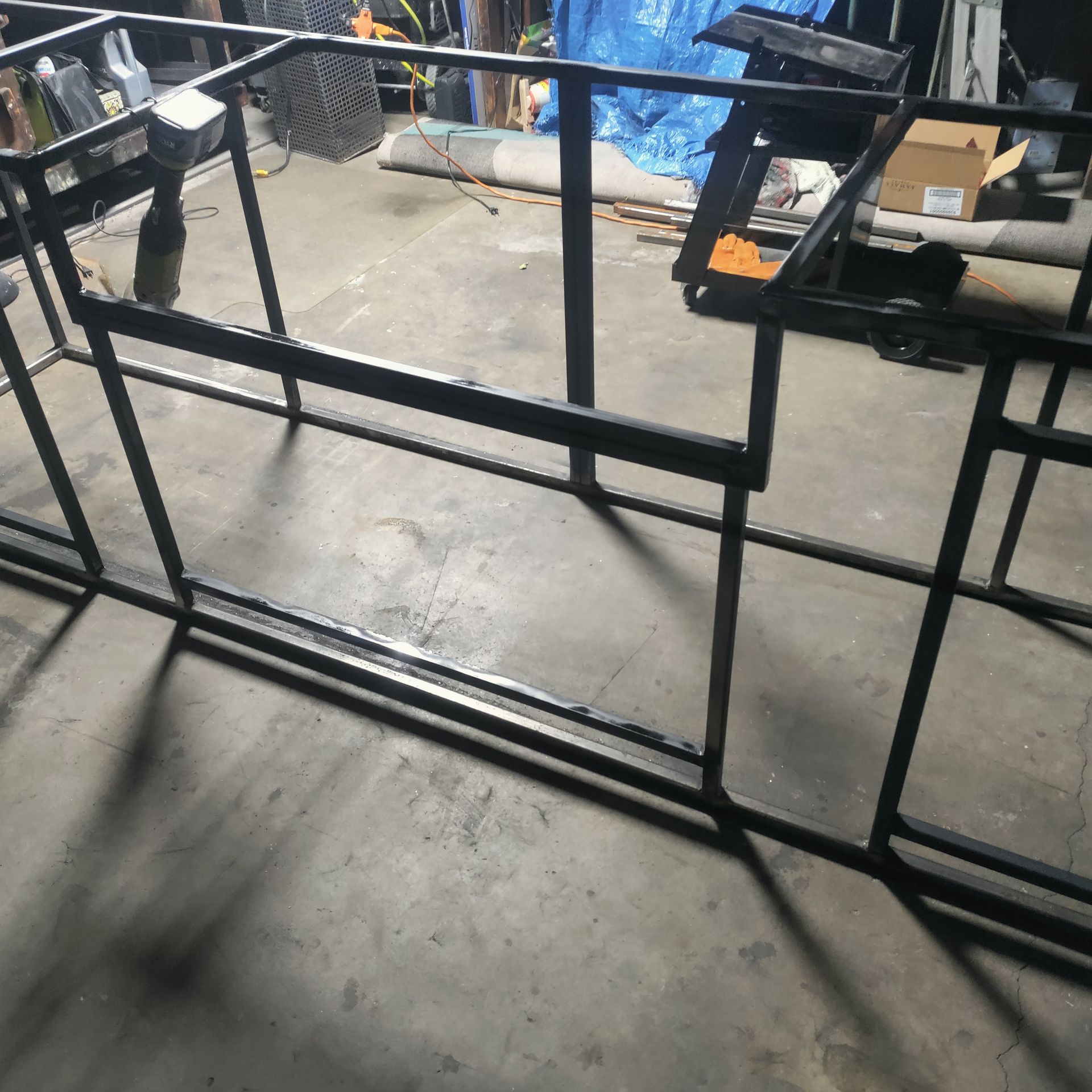 Black metal frame structure in a concrete-floored workshop.