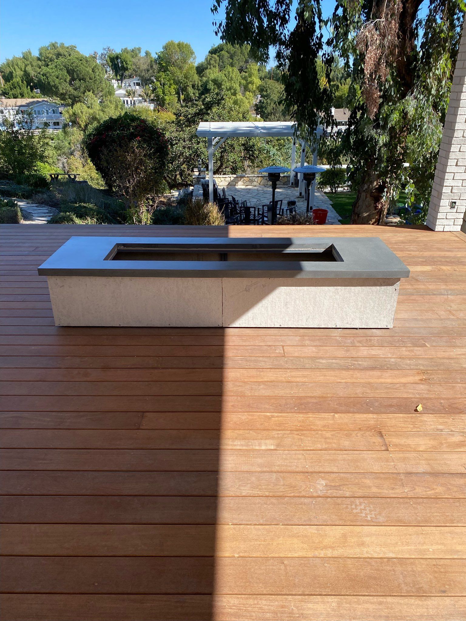 Fire pit on a wood deck with a view of trees and homes.
