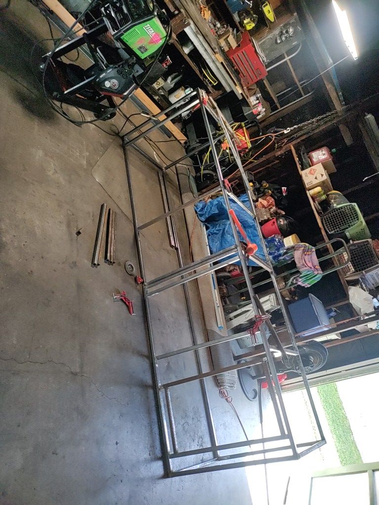 Metal shelving frame in a garage, with welding equipment in the background.