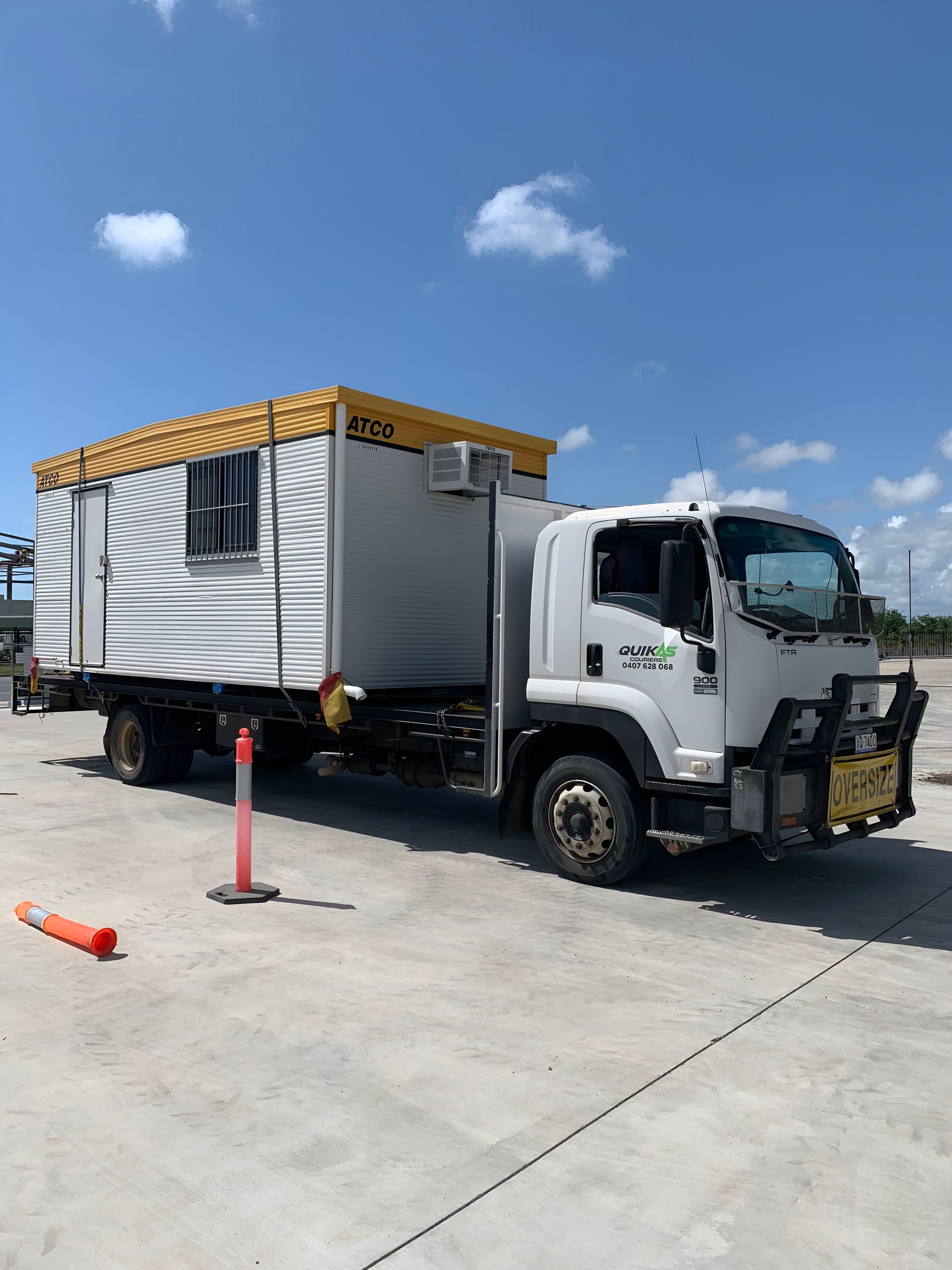White truck with a yellow-topped cabin on a concrete surface under a blue sky. — Quik As Couriers in Airlie Beach, QLD