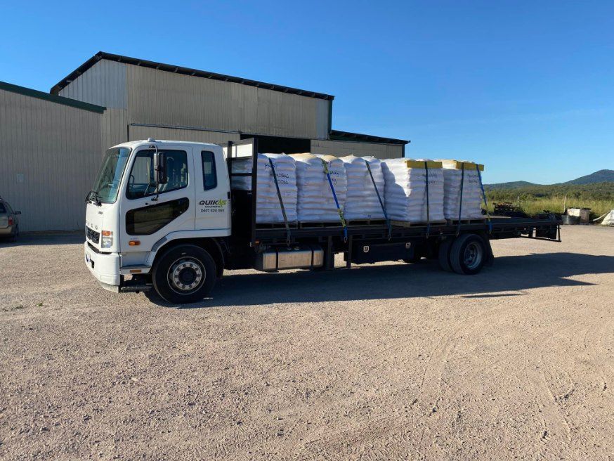 White Flatbed Truck Loaded With Wrapped Materials — Quik As Couriers in Rosella, QLD