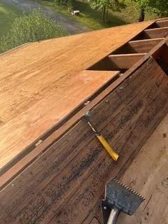 A wooden roof with a hammer and a spatula on it.