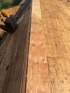 A man is sitting on top of a wooden roof.