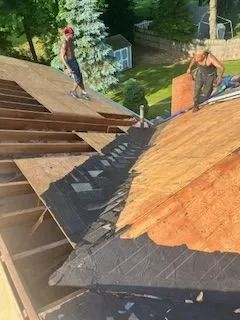 A man and a woman are working on the roof of a house.