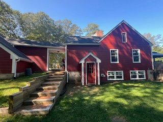 Red building with stairs and grass yard under a blue sky.