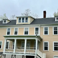 A large house with a porch and a gray roof.