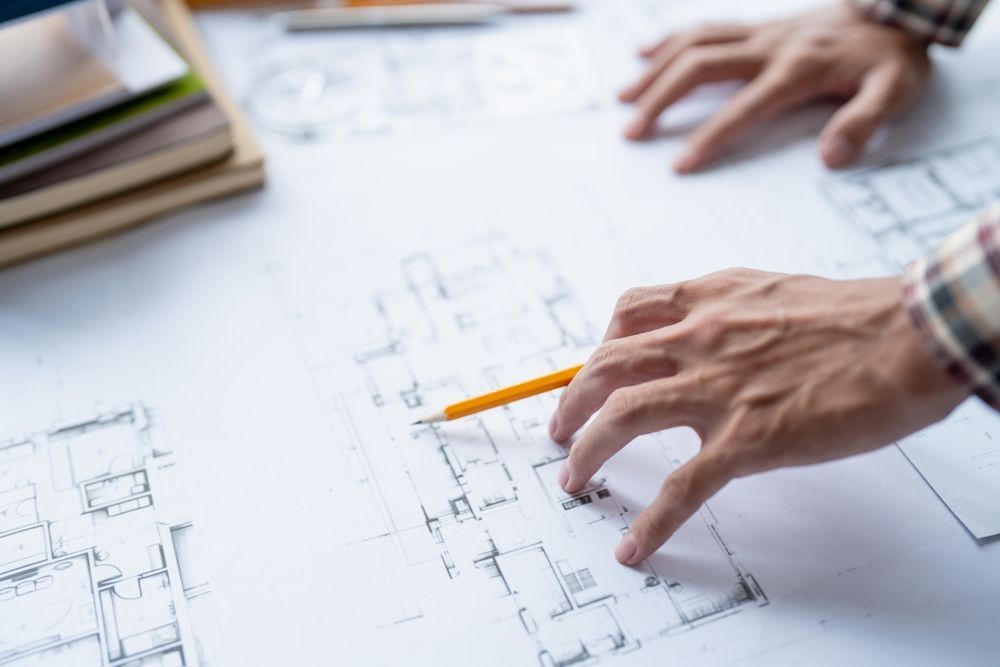 Hands Using A Pencil To Examine Architectural Blueprints On A Desk — GS Design & Drafting In Ballina, NSW