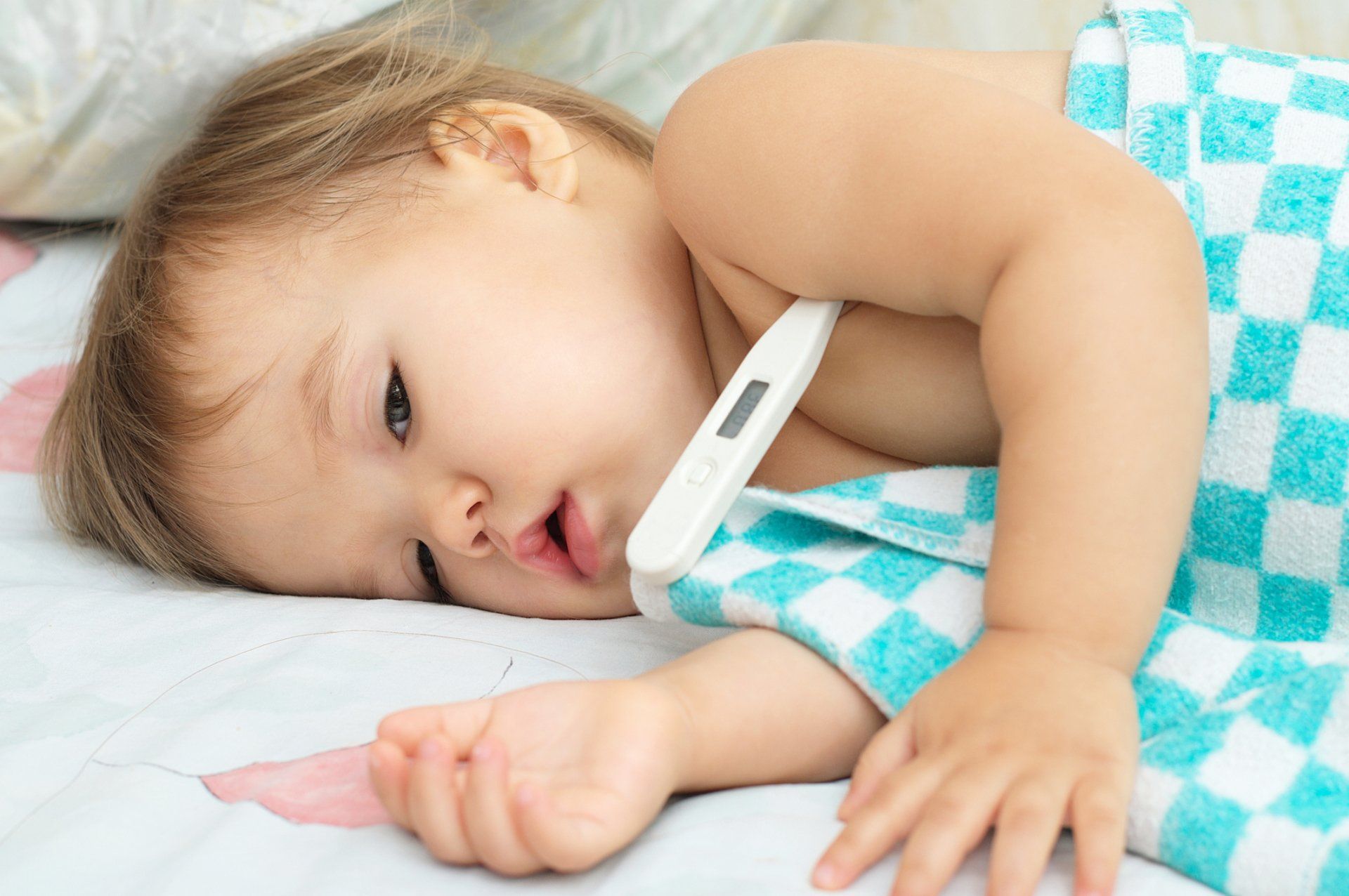 baby laying down with thermometer in armpit