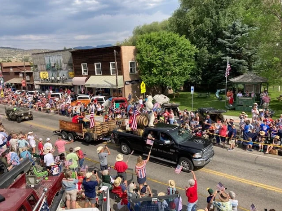 A large crowd of people are watching a parade in a small town.