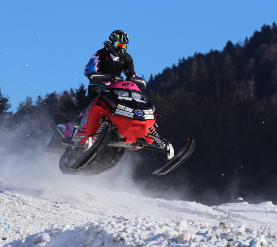 A person riding a snowmobile with the word arctic on the front