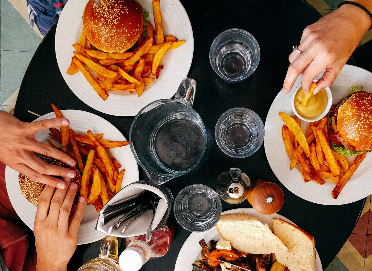 A group of people are sitting at a table eating hamburgers and french fries.