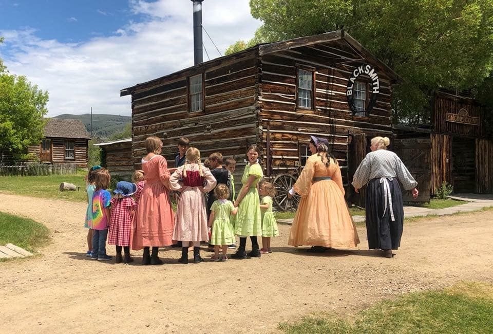 A group of people are standing in front of a log cabin.