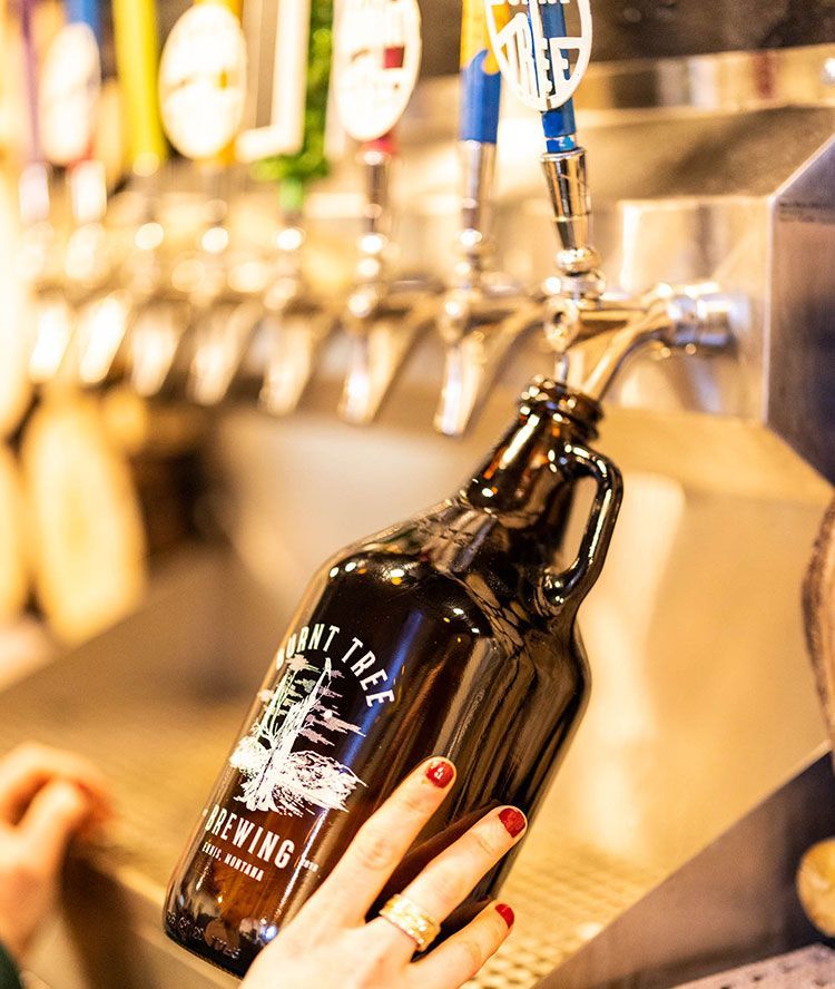 A person is pouring a bottle of beer from a tap