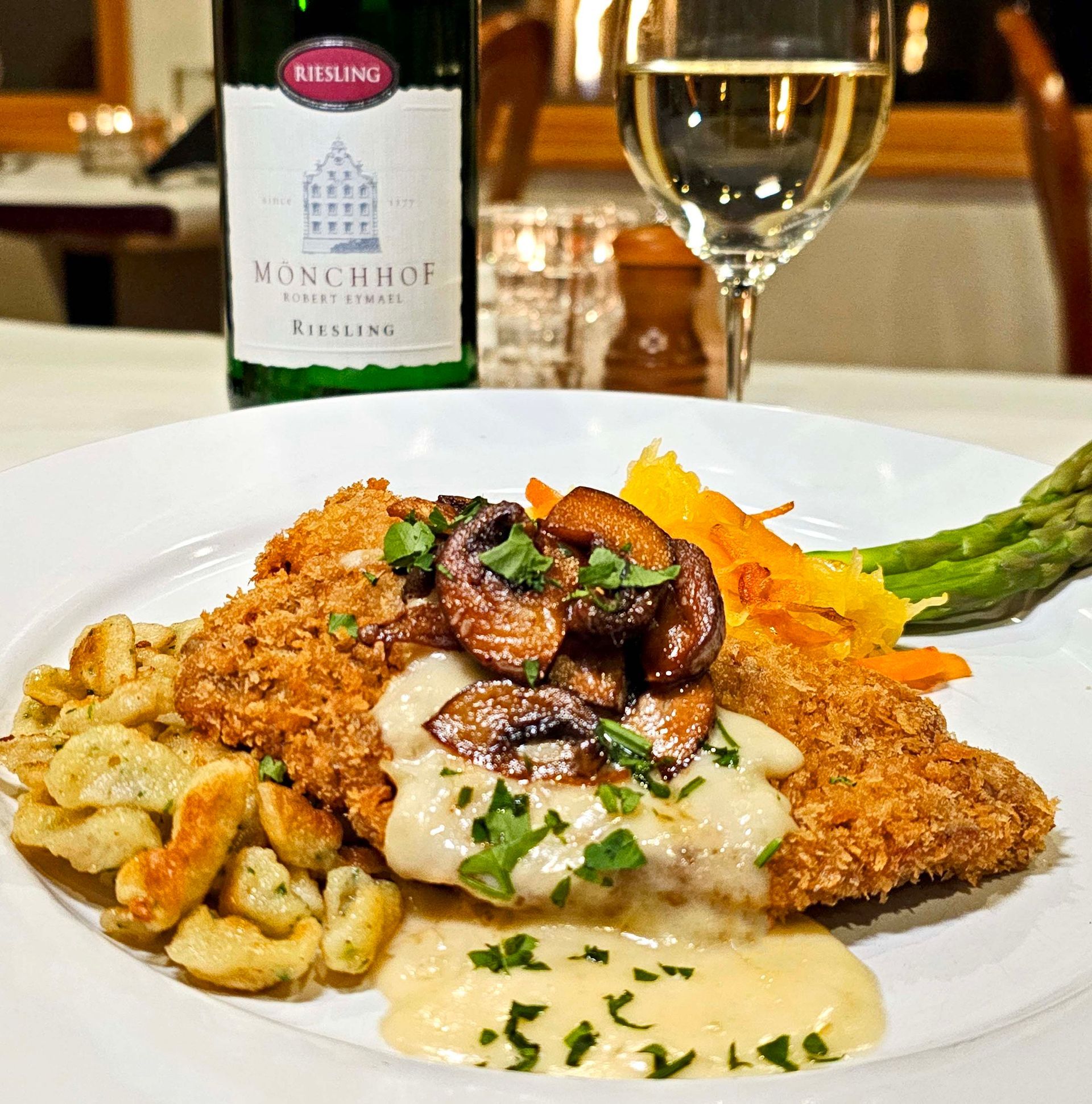 A plate of food with a bottle of riesling in the background