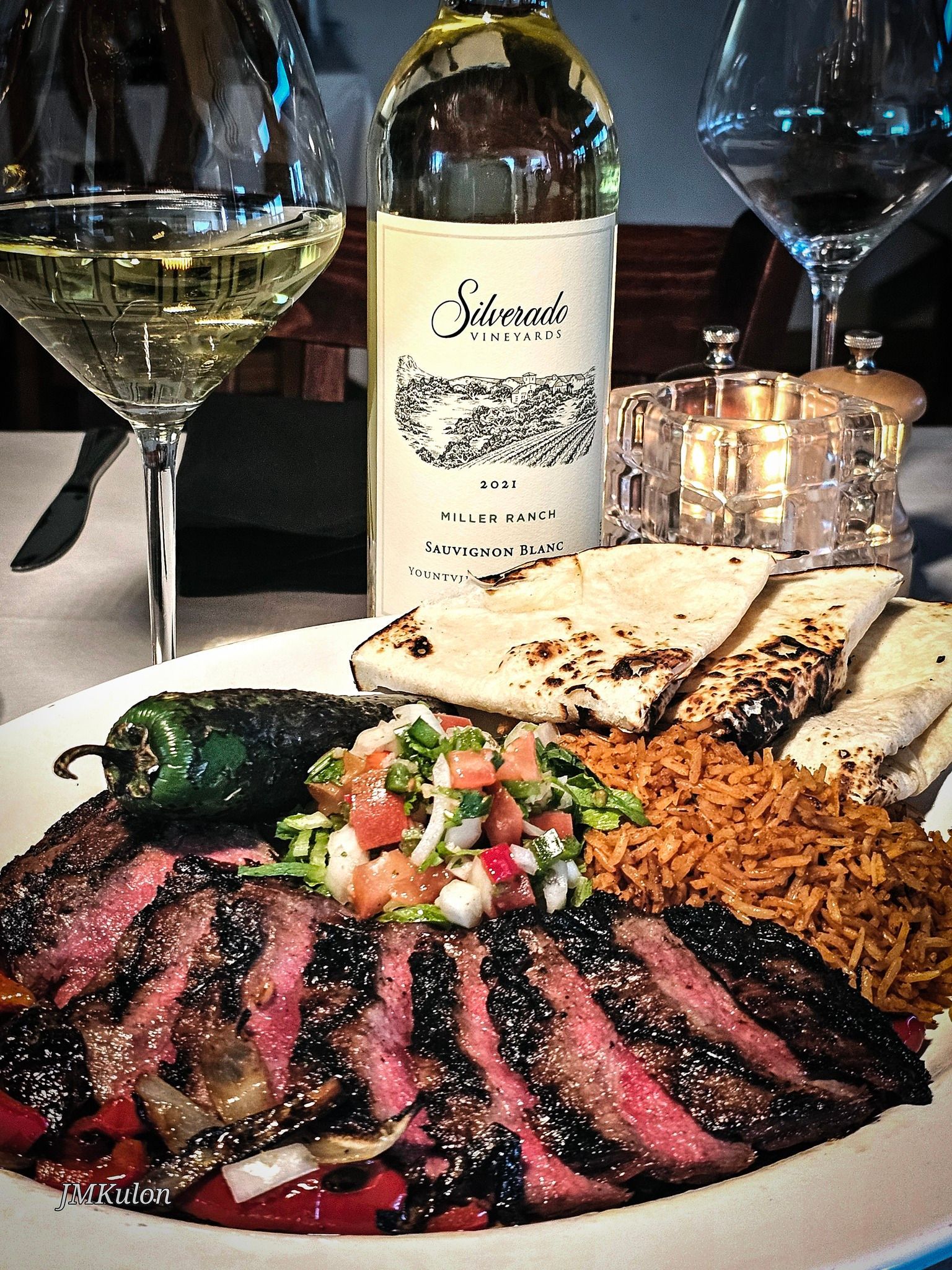 A plate of food with a bottle of wine in the background