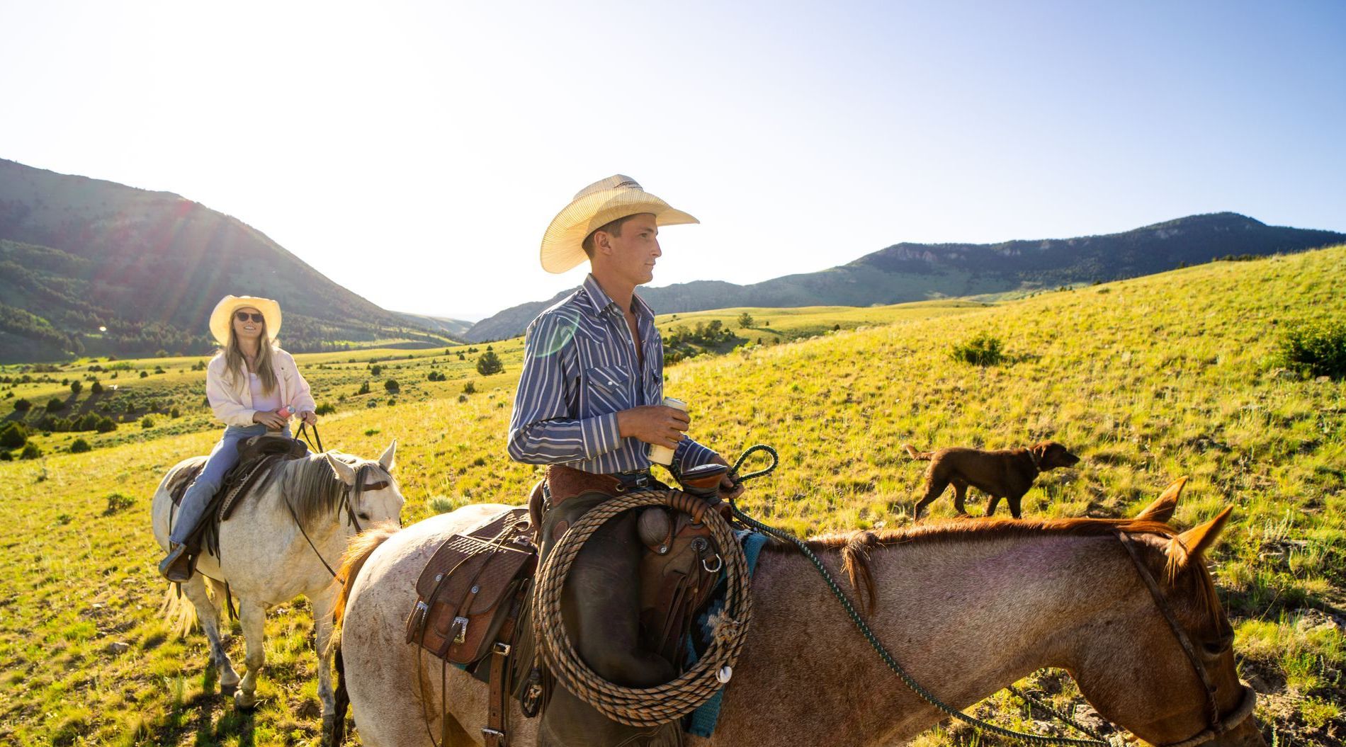 A man and a woman are riding horses in a field.