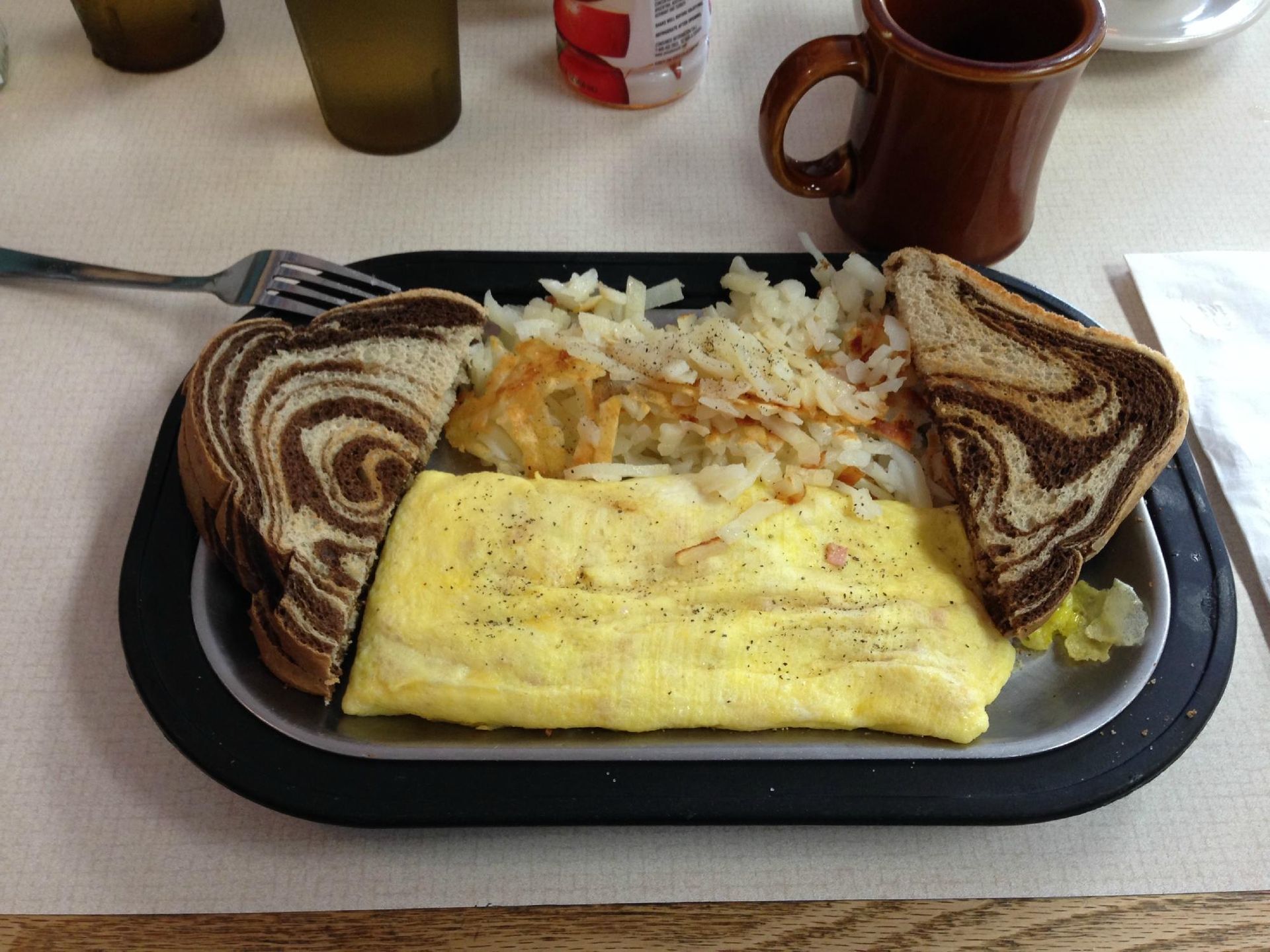 A plate of food with eggs , hash browns and a sandwich on a table.