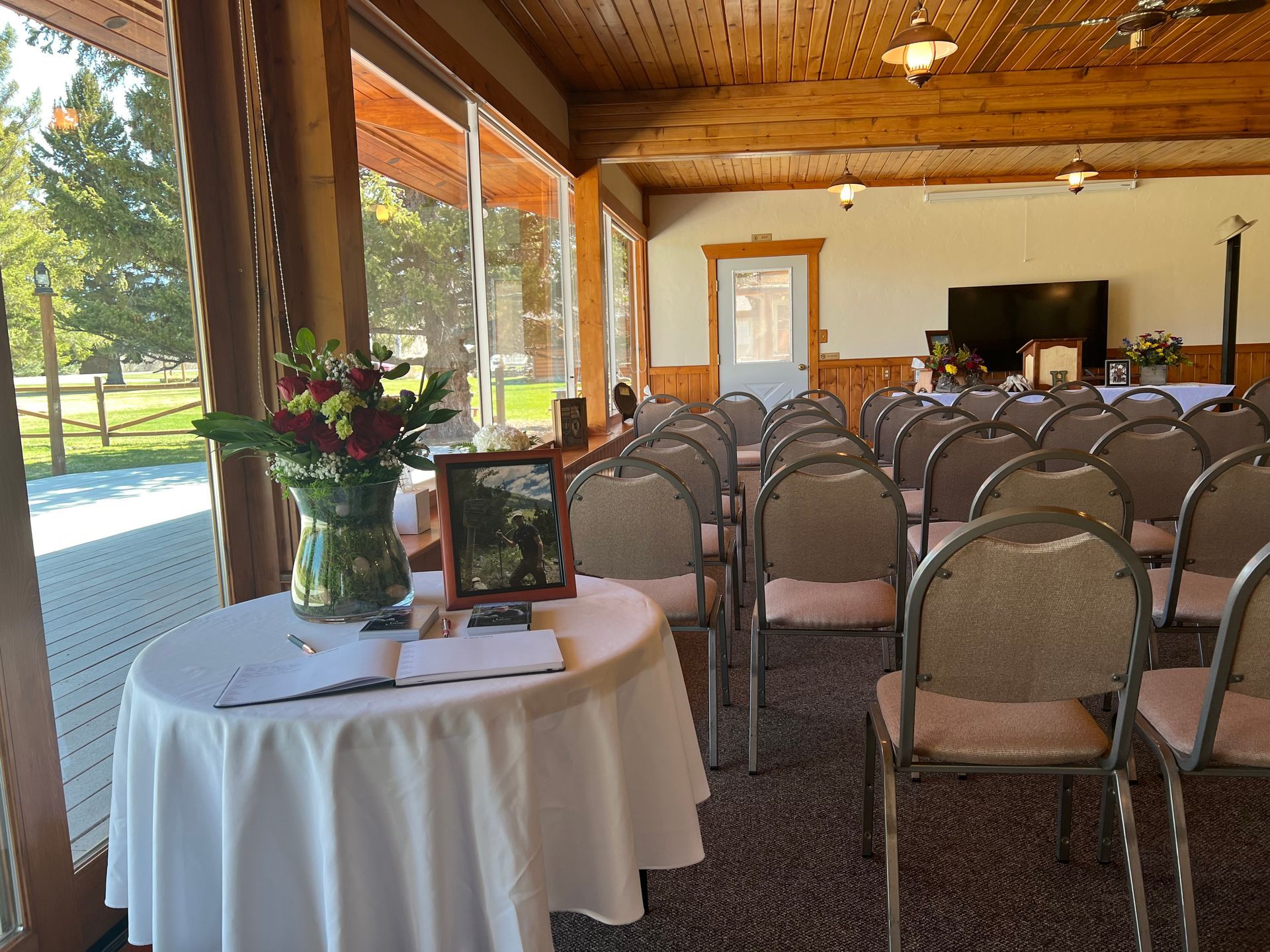 A room with rows of chairs and a table with a vase of flowers on it.