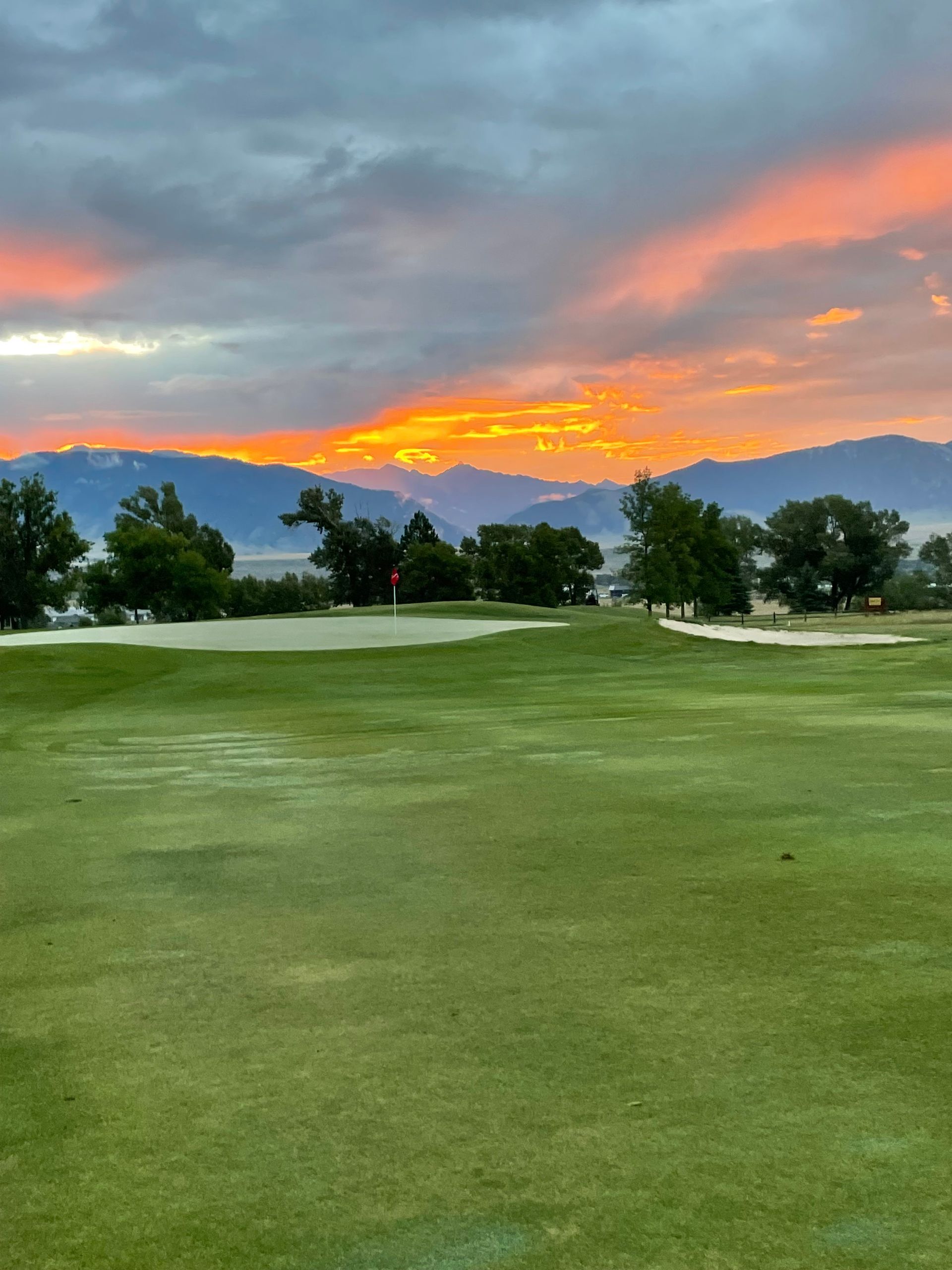 A sunset over a golf course with mountains in the background