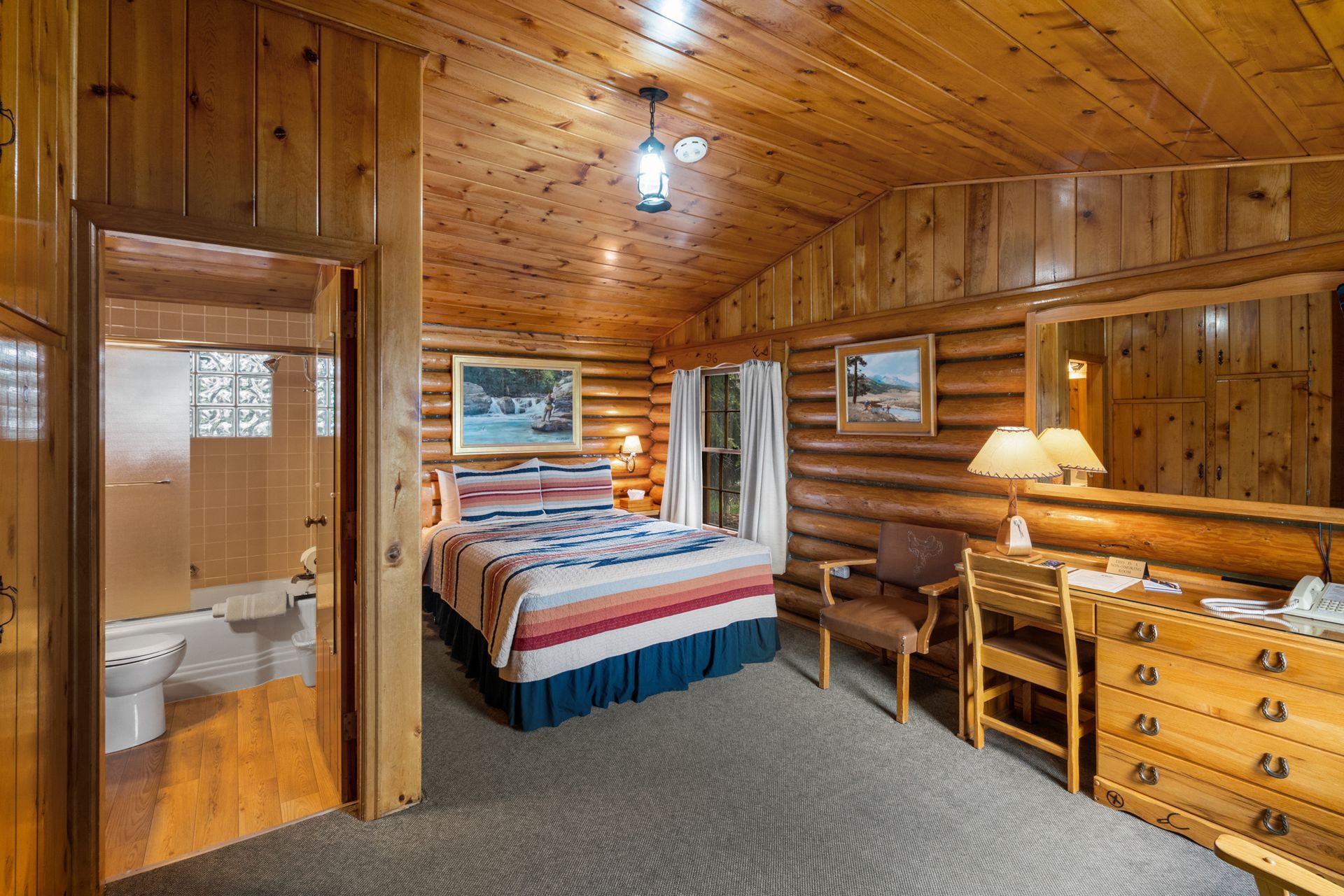 A bedroom in a log cabin with a king size bed and a bathroom.
