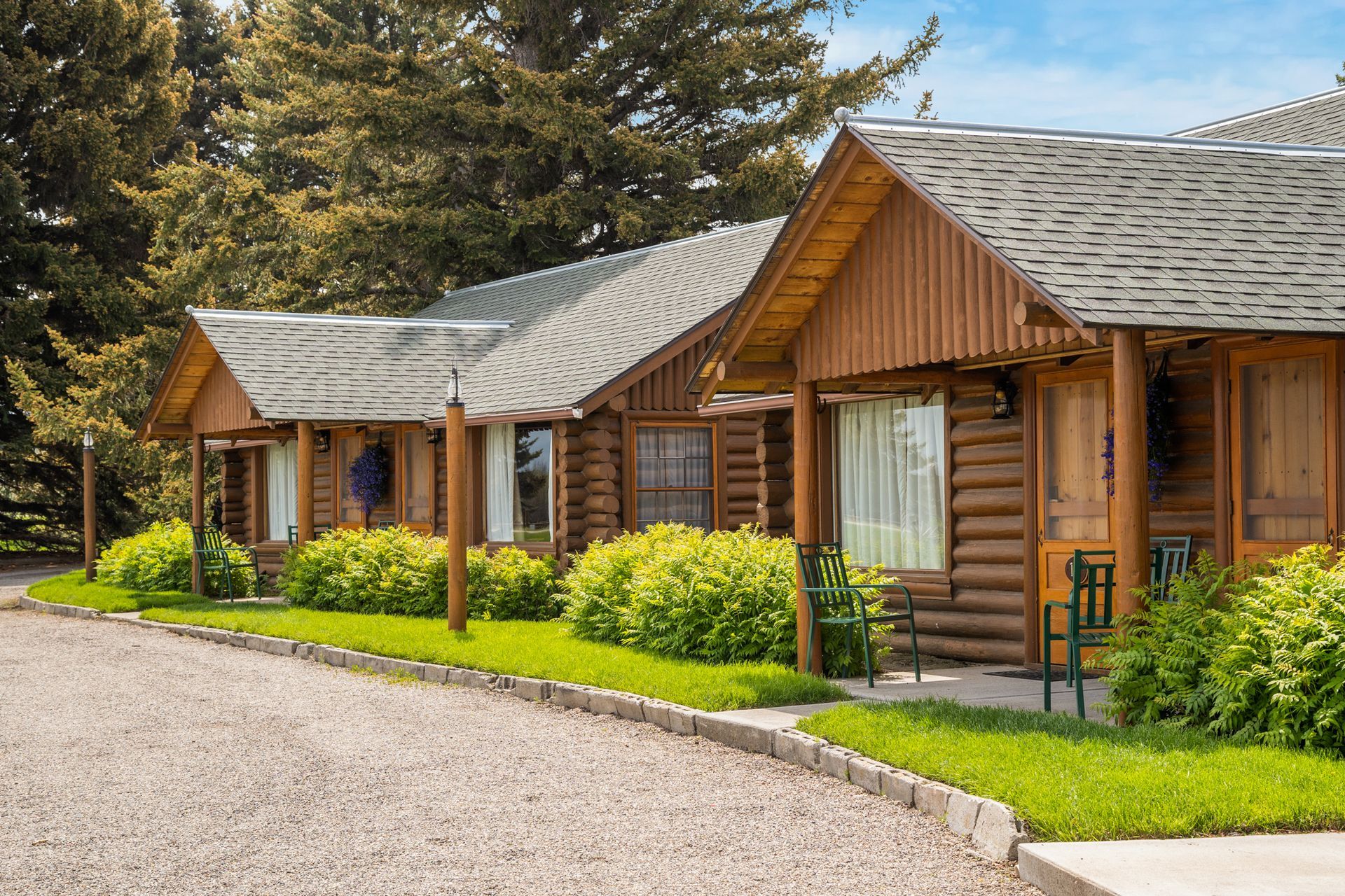 A row of log cabins sitting next to each other on a gravel road.