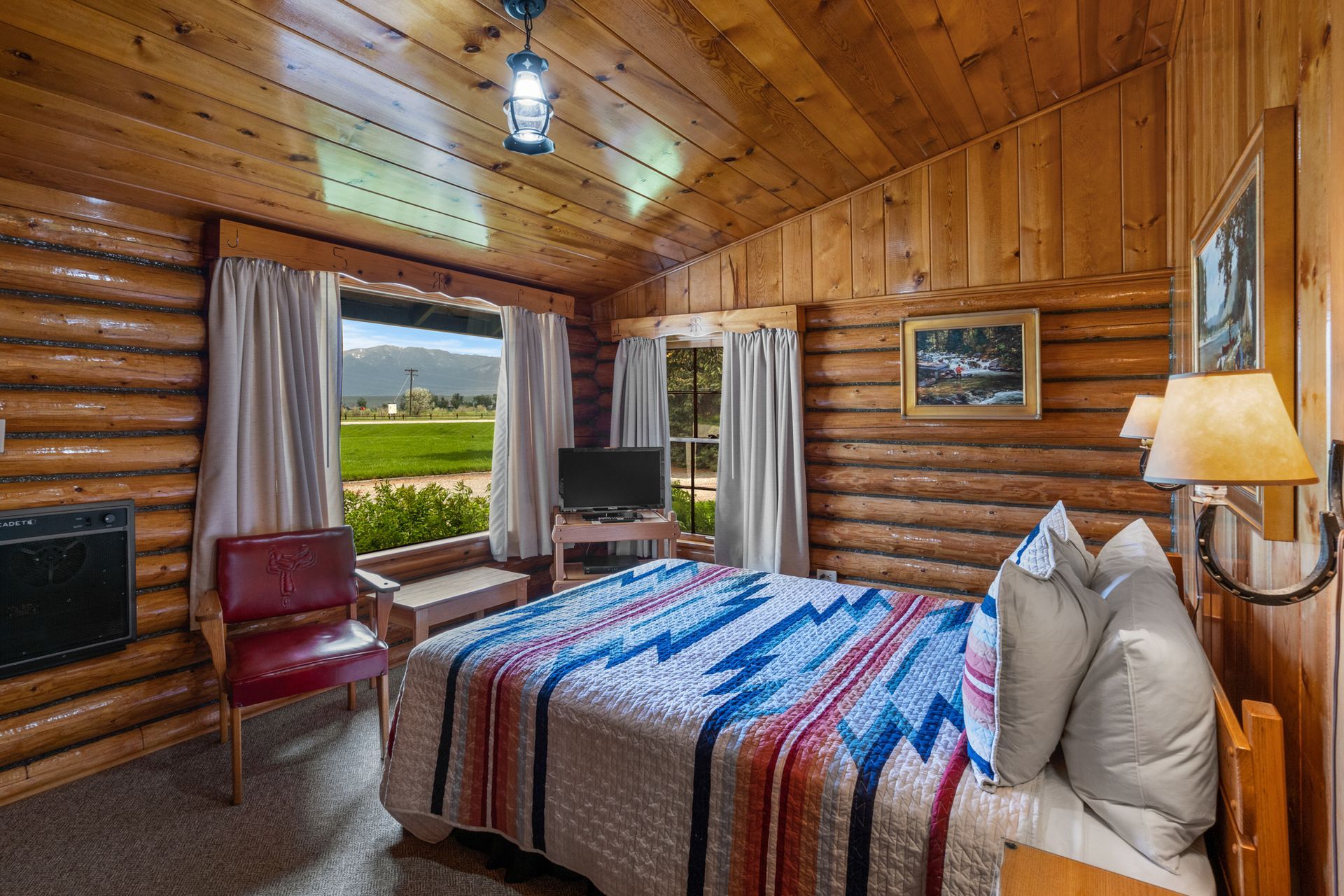 A bedroom in a log cabin with a king size bed and a television.